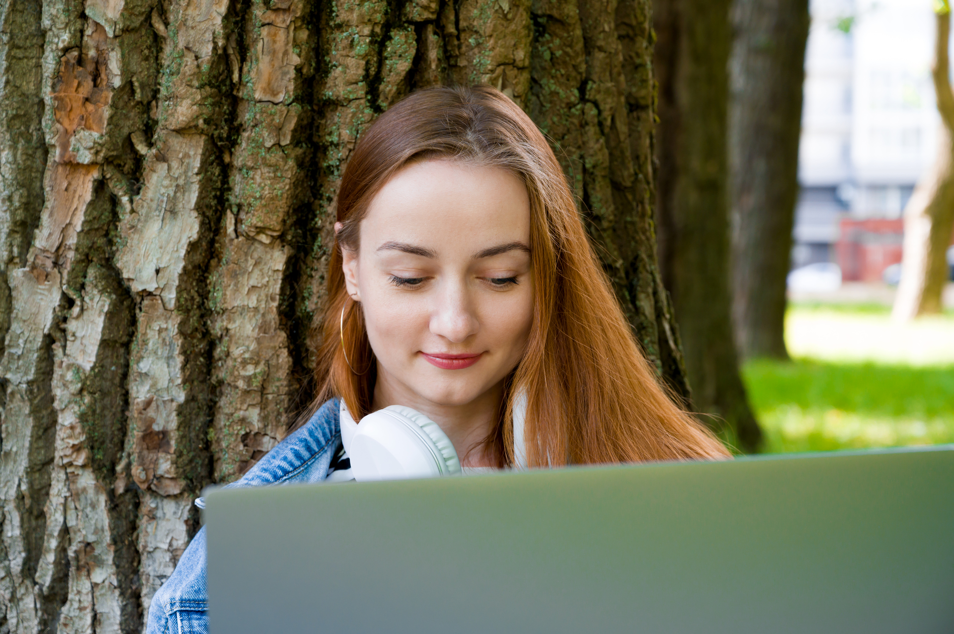 Studentka Politechniki Śląskiej pod drzewem z laptopem na kolanach